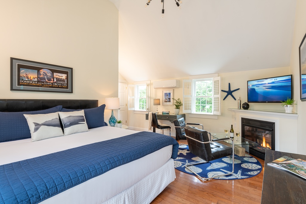 Stay at the Best Cape Cod Bed and Breakfast this fall. Interior guest room with bed and white bedspread, two chairs, and television.