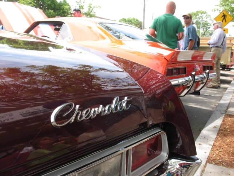 the back of an old brown Chevy, next to an orange car