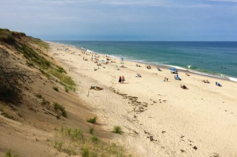 a beach with lots of people sunbathing and walking
